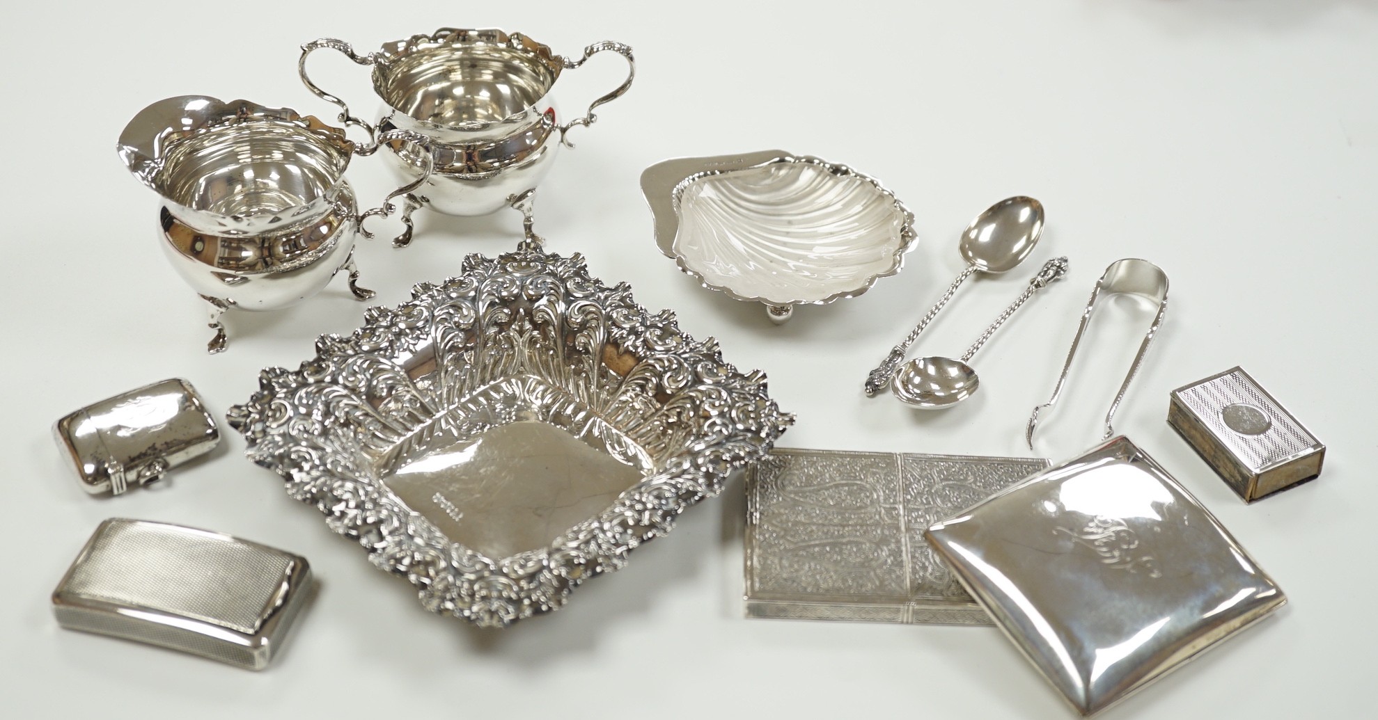 A small group of collectable silver including a repousse bonbon dish, 13.5cm, cigarette case, silver cream jug and sugar bowl, butter shell, vesta case, match sleeve, two apostle teaspoons and a George III curved silver